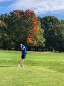 Golfer on the green with colorful trees in the background