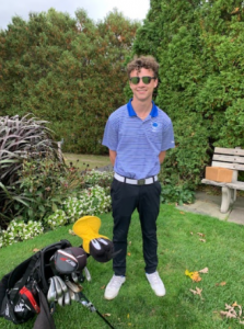 Student standing in golf uniform with sunglasses
