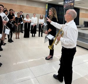 Brian Swanhall holding trumpet and directing students