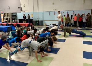 students do push ups at latham ridge with a service member.