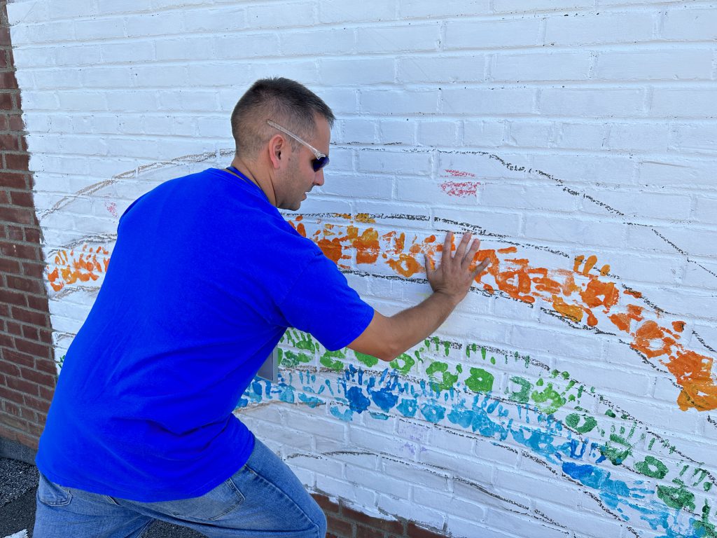 Blue Creek Principal Mr. Turcio puts his handprint on the mural for International Peace Day.