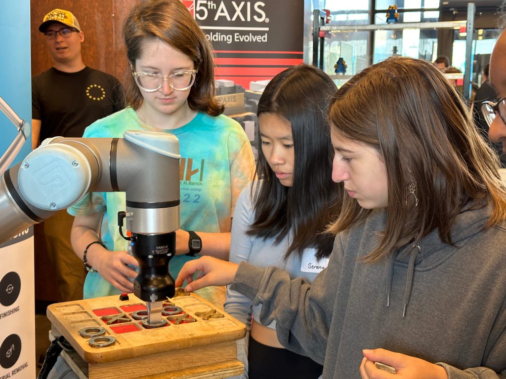 Three students work together on a piece of equipment.
