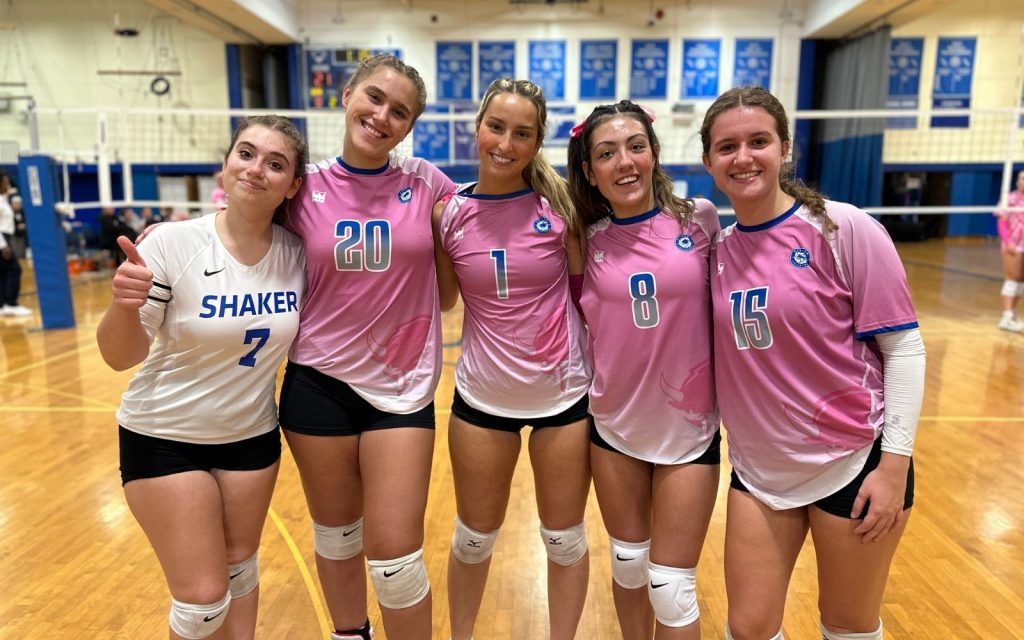 An image of five Shaker girls varsity volleyball players wearing pink jerseys on the court.