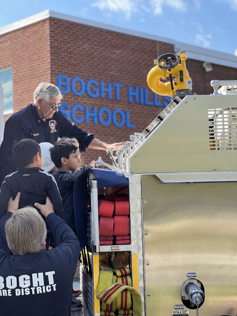 An image of fire officials helping students up onto a fire truck.