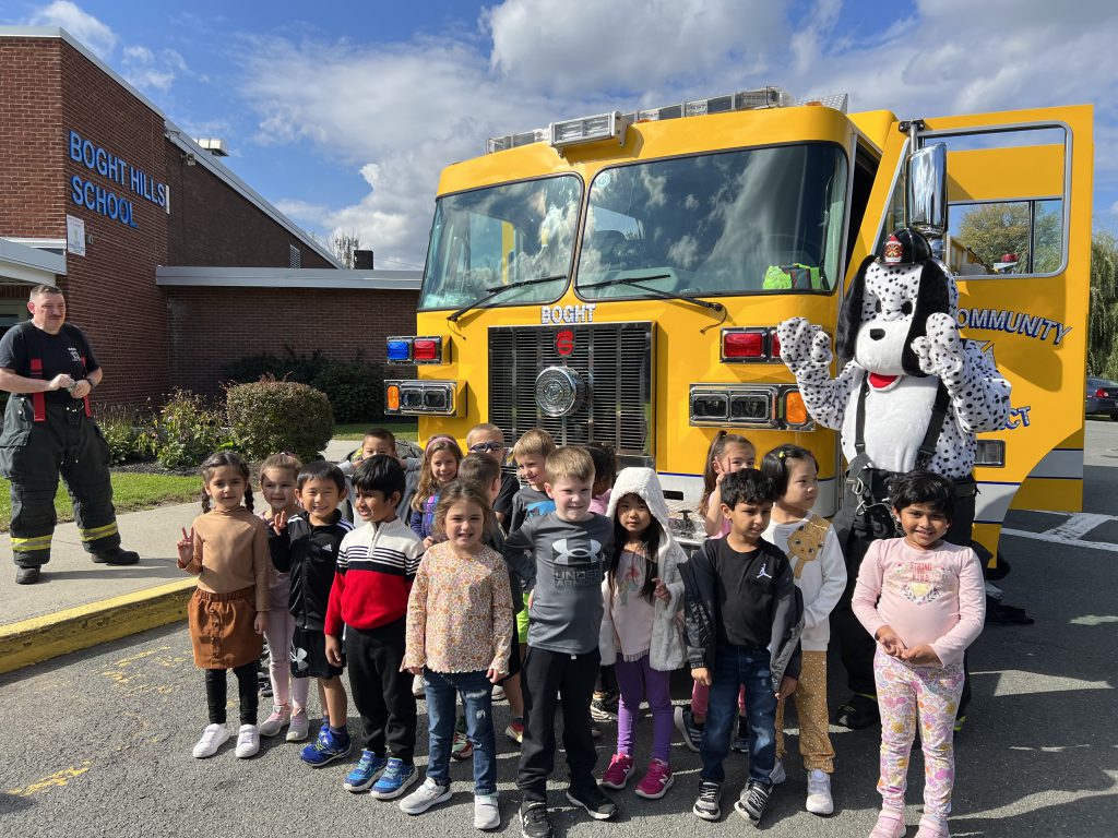 An image of a class of students posing in front of a fire truck.