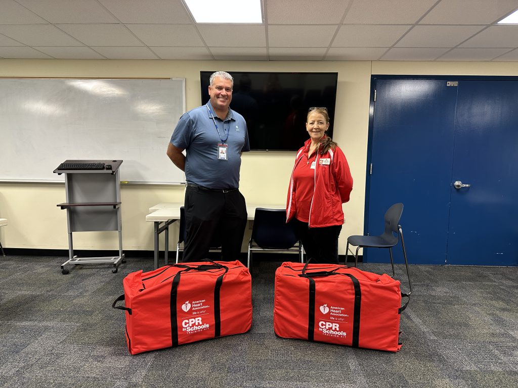 An image of Shaker High School Athletic Director Sean Colfer accepting a donation of two CPR kits from St. Peter's Healthcare and the American Heart Association.