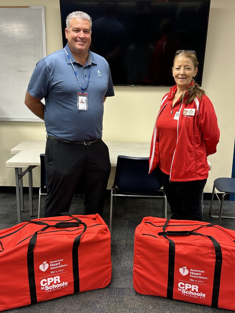 An image of Shaker High School Athletic Director Sean Colfer accepting a donation of CPR kits with a representative from the American Heart Association.