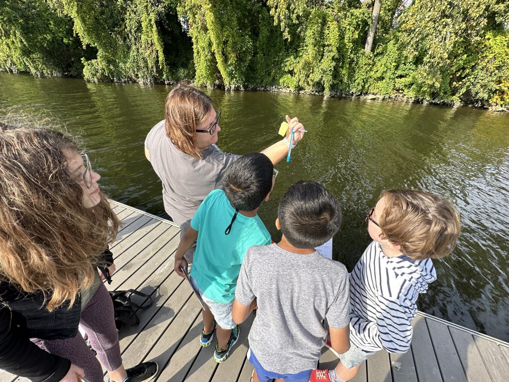 An image of a teacher showing students a thermometer.