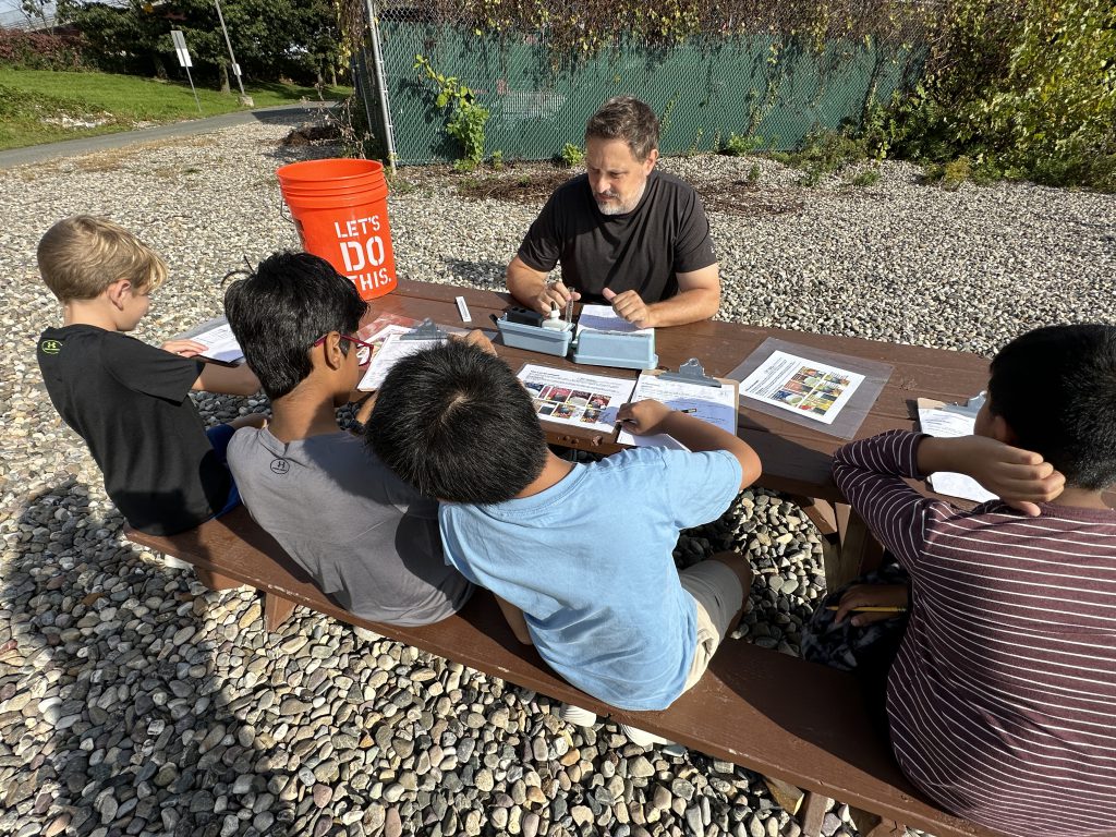 An image of four students testing water samples with a teacher.
