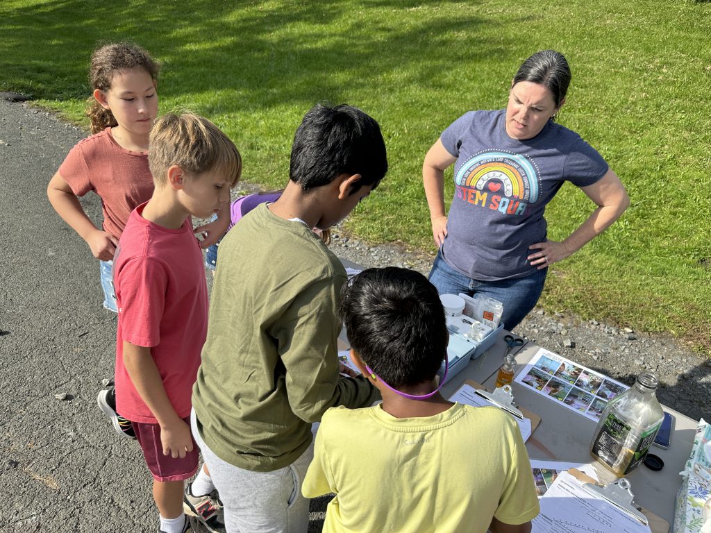 An image of four students conducting experiments with a teacher.