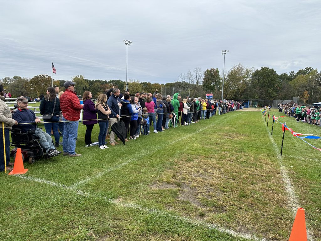 An image of parents lining the country country course to cheer for the students.