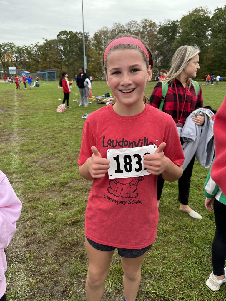 A student poses with thumbs up after winning the girls 5th grade cross country race.