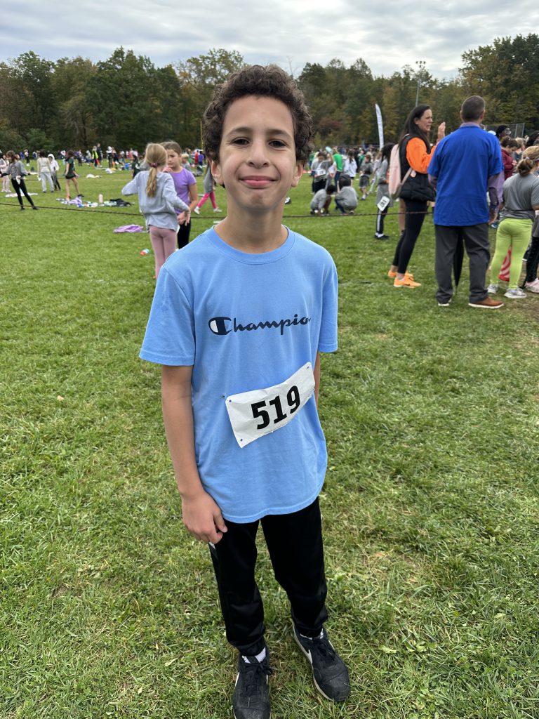A student poses after winning the boys 5th grade cross country race.