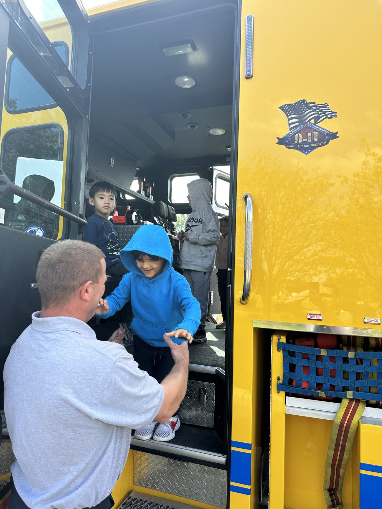 An image of a fire official helping a student get off of a fire truck.