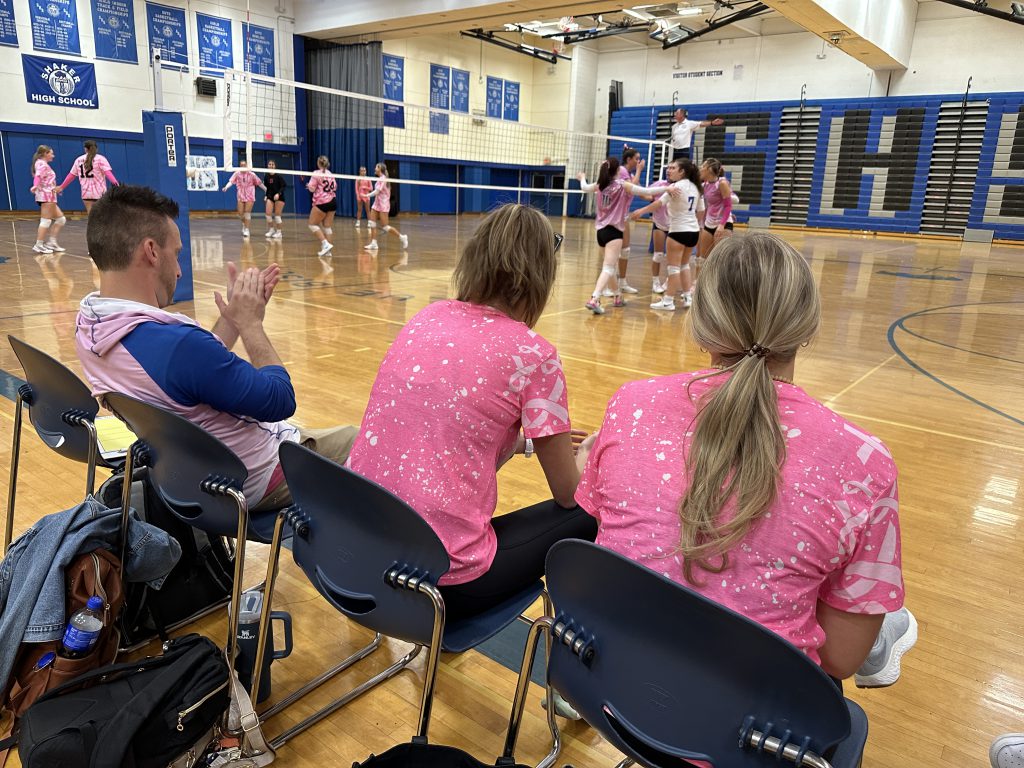 An image of the Shaker coaching staff in pink, cheering on their players.