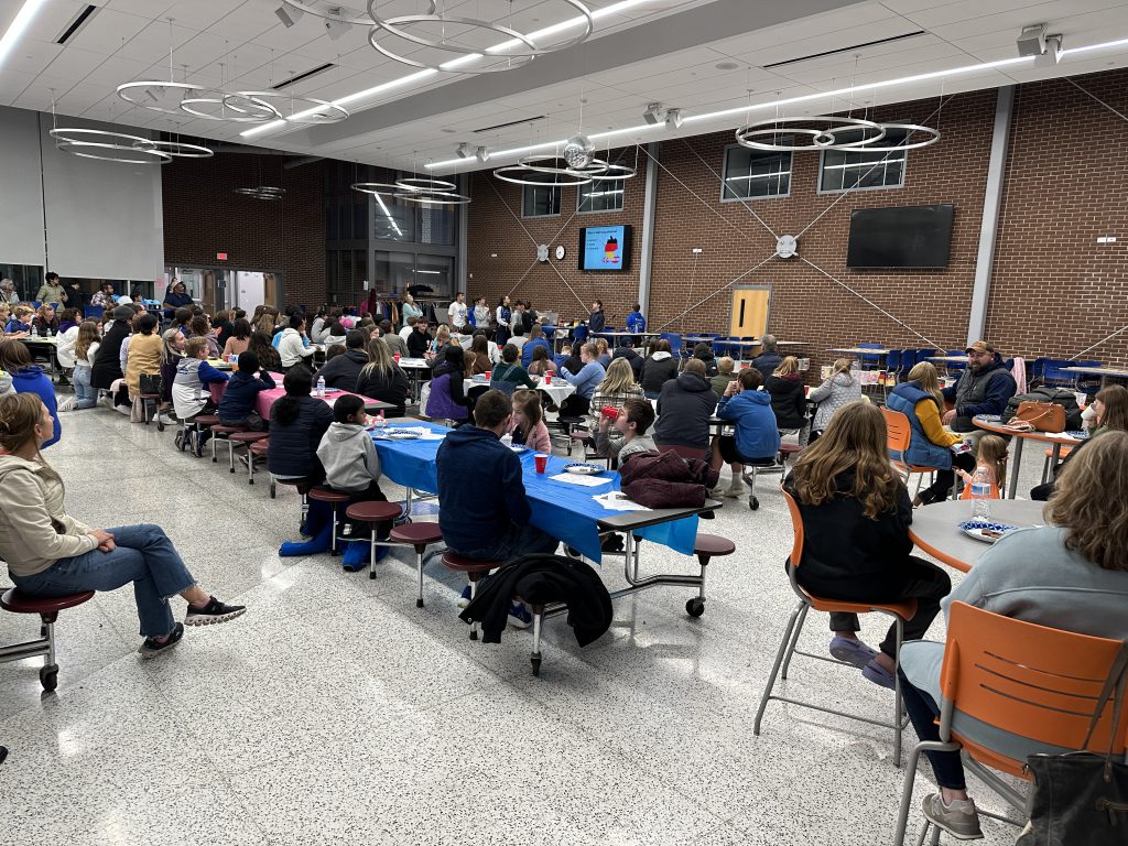 An image of hundreds of people in a cafeteria listening to a presentation on Martinstag.