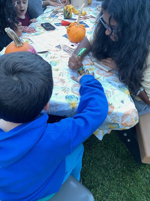 An image of a student drawing henna on another student's hand.