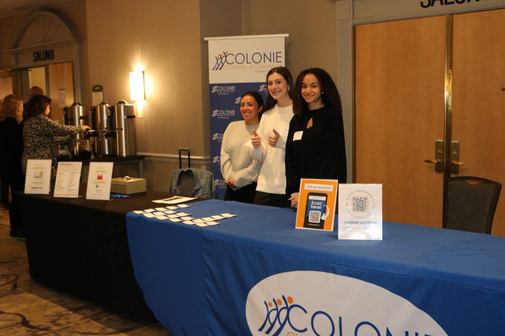 An image of three students assisting with registration at the Emerging Leaders Summit.