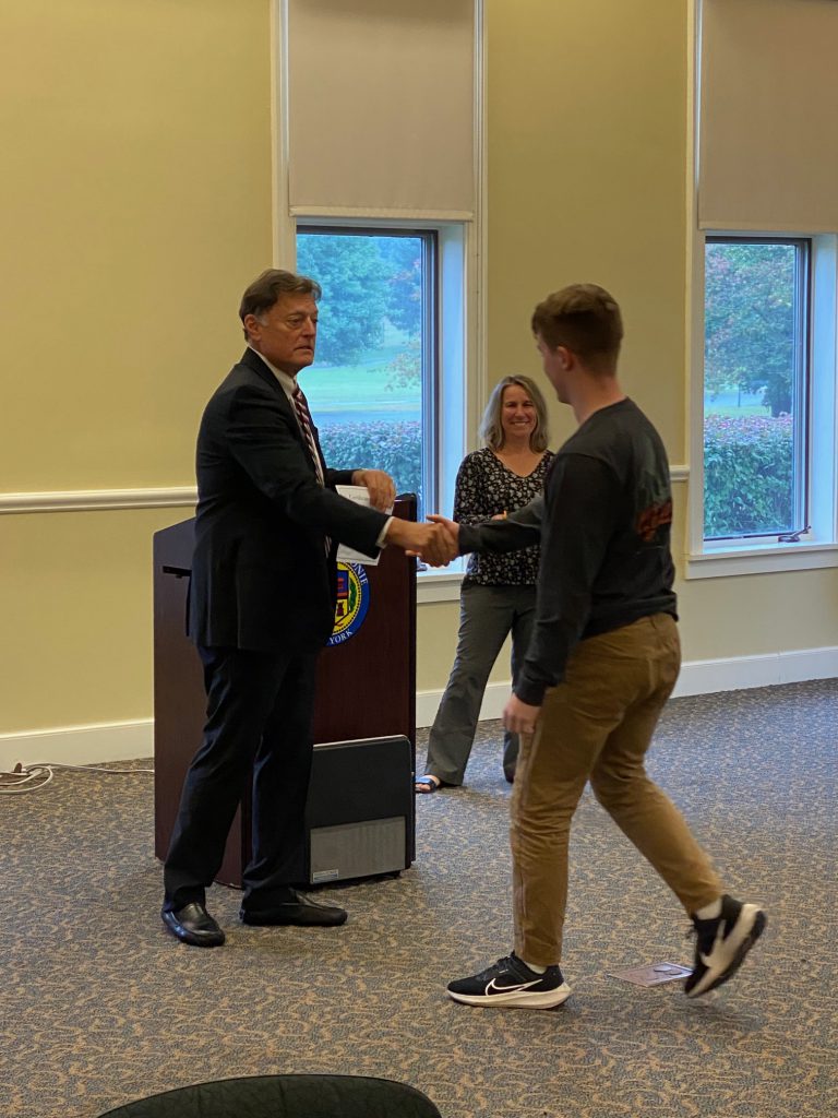 An image of a Shaker student shaking hands with Colonie Town Supervisor Peter Crummey.
