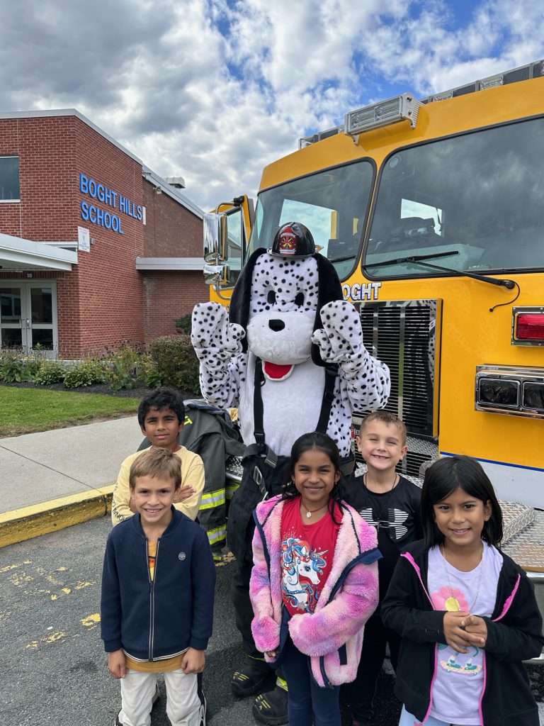 An image of a group of students posing with the fire dog mascot in front of a fire truck.