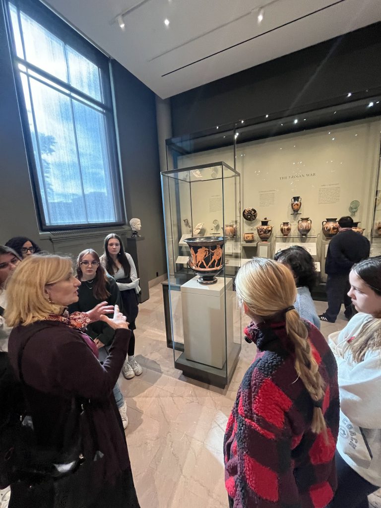An image of a guide explaining some of the works of art in the museum to a group of students.