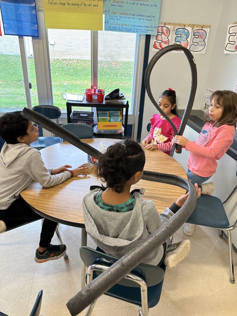 An image of students doing a hands on activity to create their own rollercoasters.