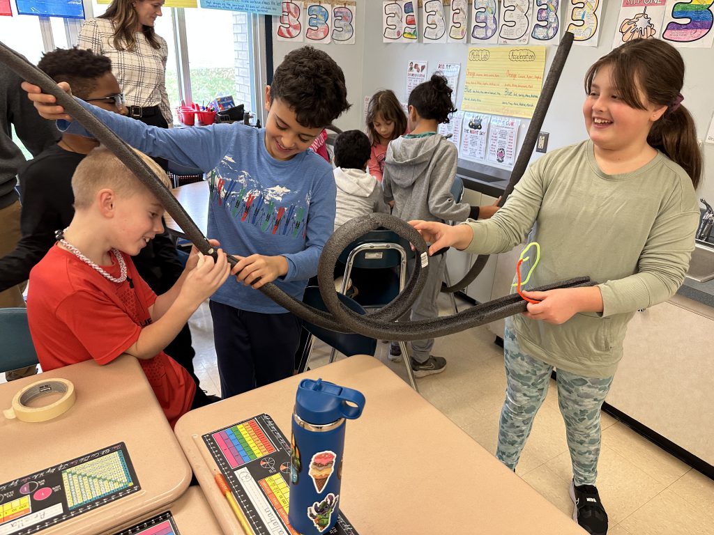 An image of students working together on their handmade rollercoasters.