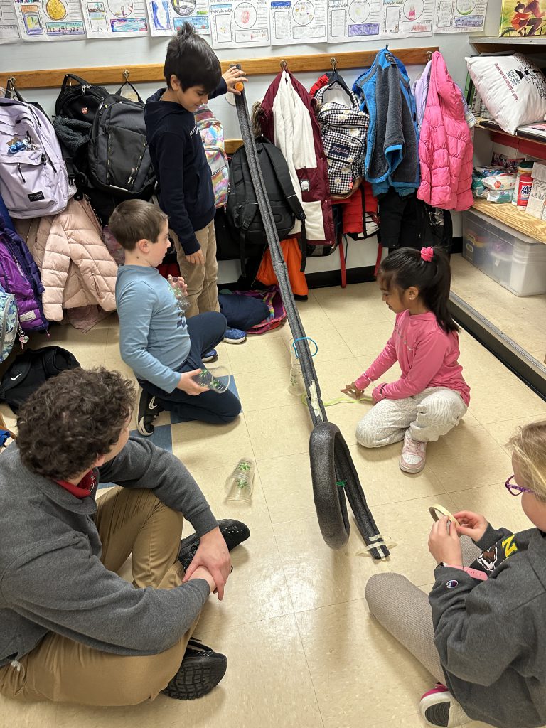 An image of students testing their handmade rollercoaster.