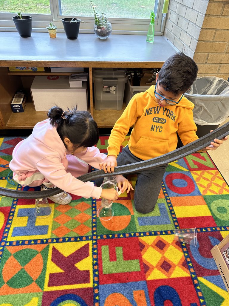 An image of two students using cups to prop up their rollercoaster track.