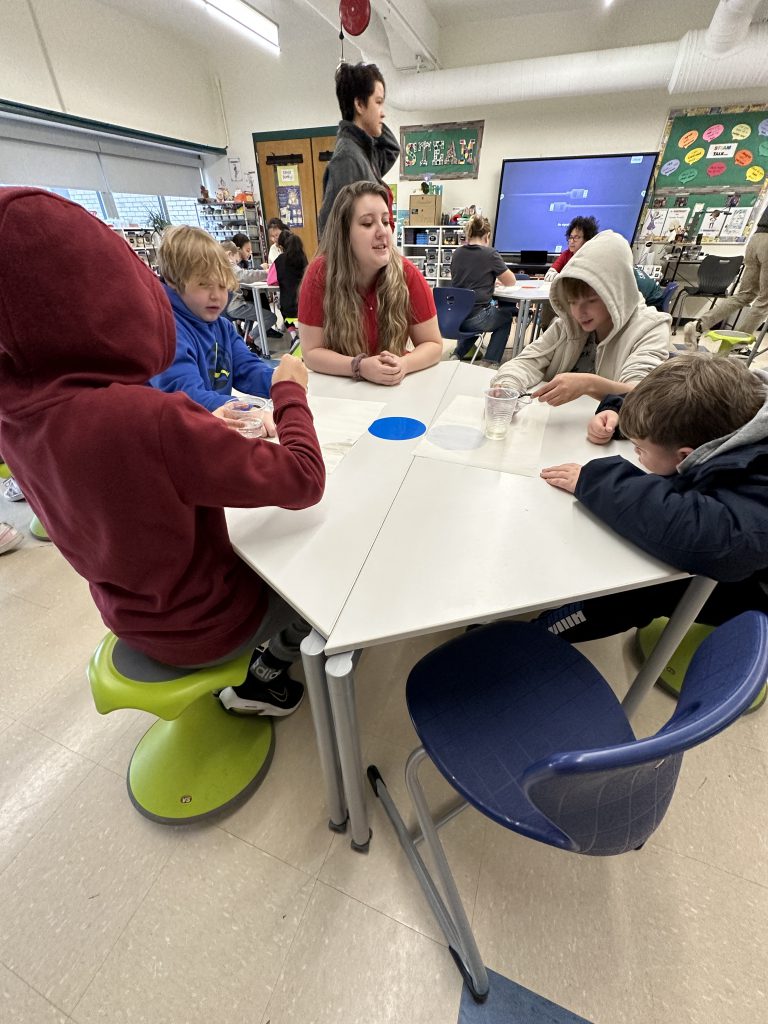 An image of an RPI student advising two teams of fifth graders during their experiment.