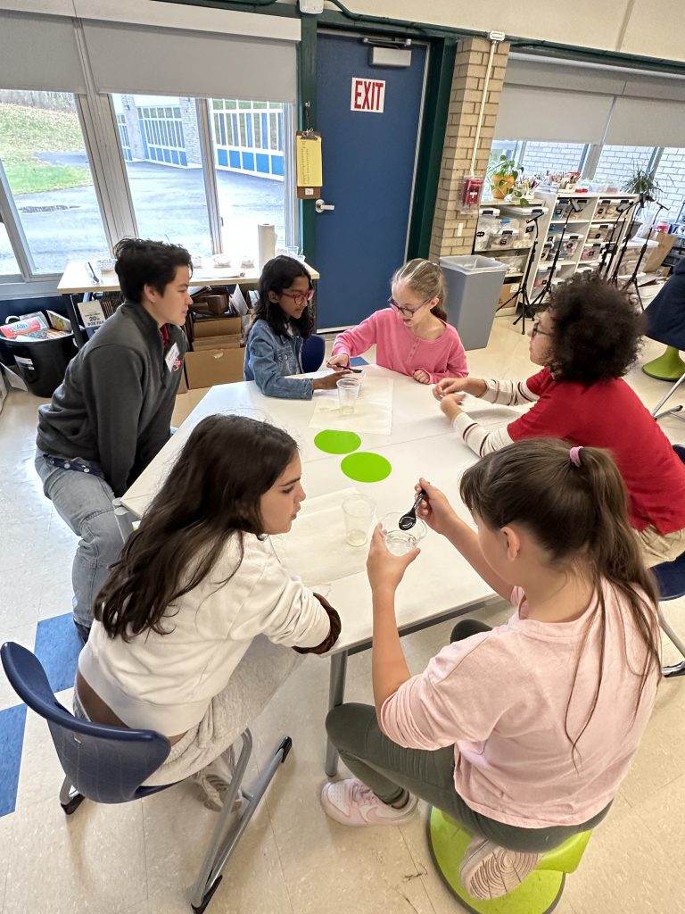 An image of two RPI engineering students working with a group of fifth graders.