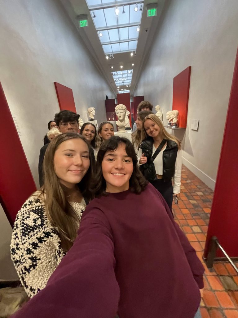 An image of students taking a group selfie in an art gallery.