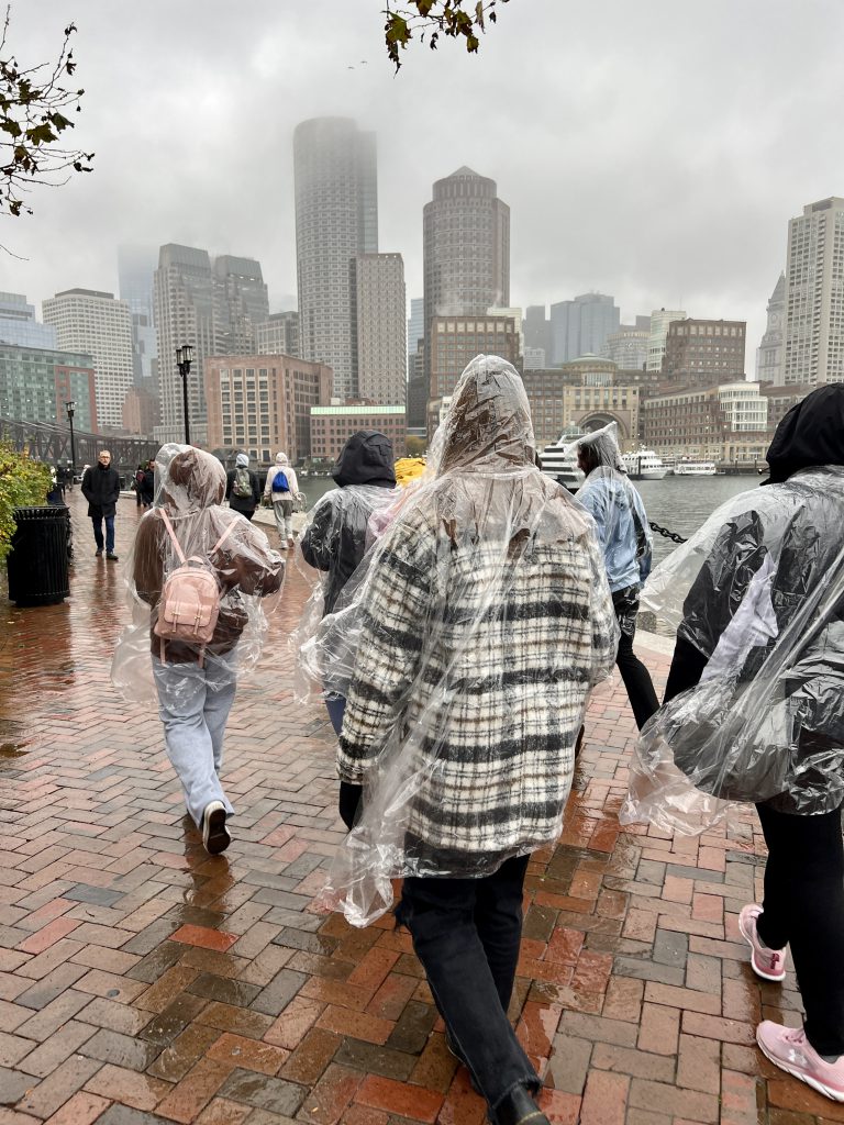 An image of students walking in ponchos on a rainy day in Boston.
