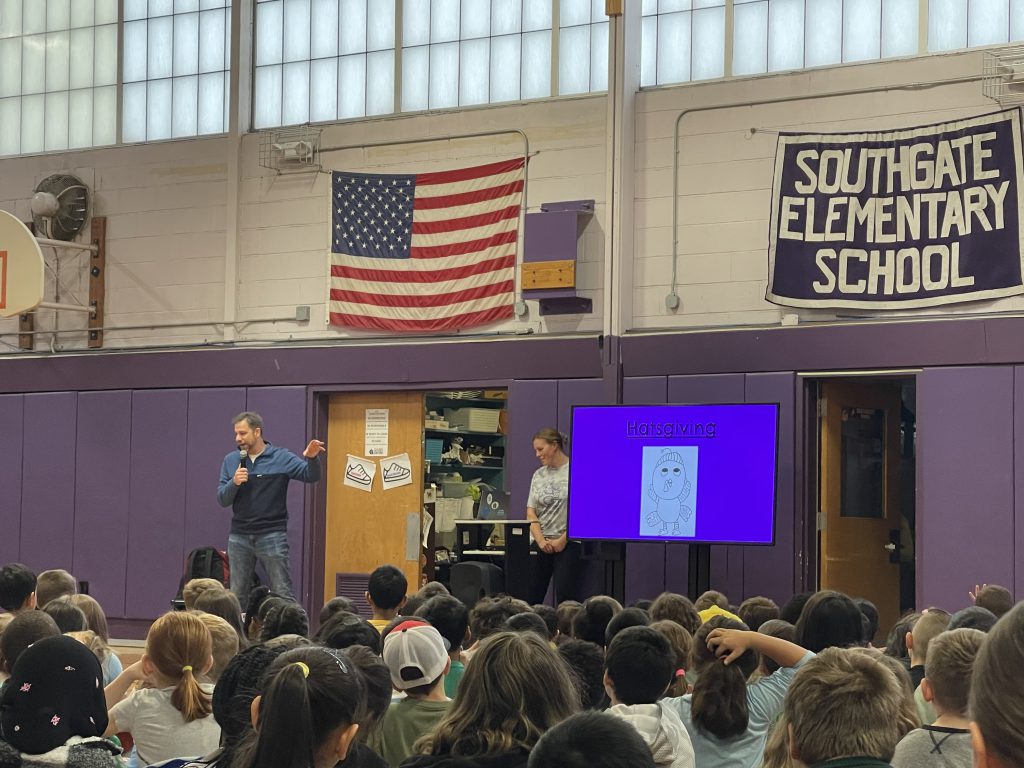 An image of a presenter speaking to Southgate students at the front of the gym.