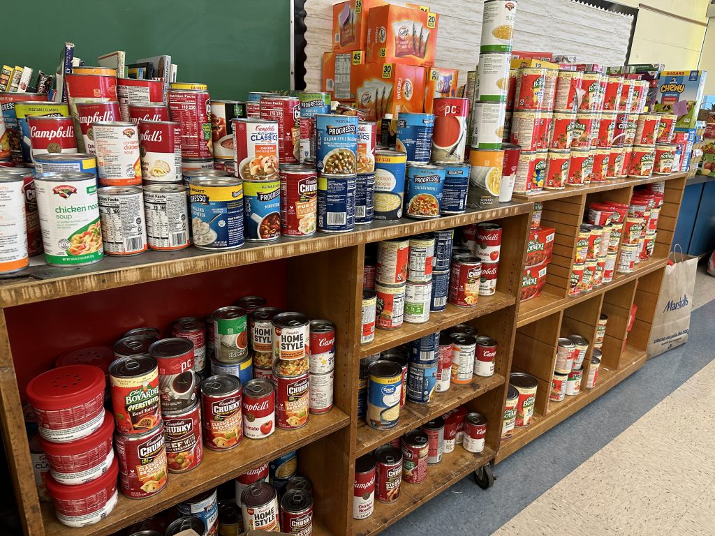 An image of soup and other canned goods lining the shelves at the food pantry.
