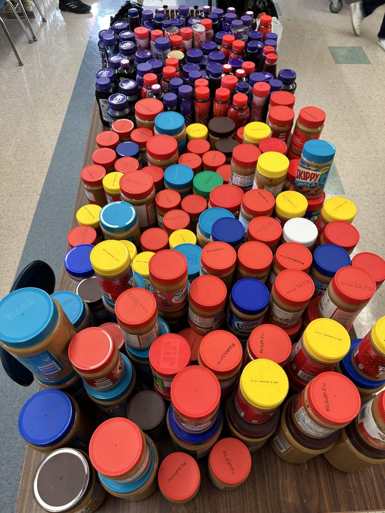 An image of peanut butter and jelly jars filling a table in the food pantry.