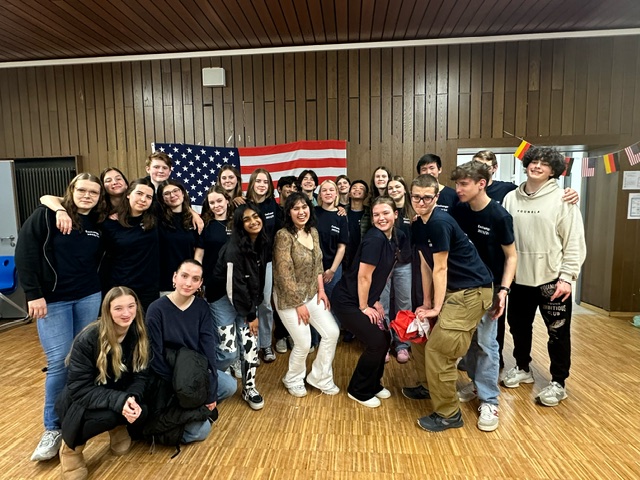 An image of students posing in front of the American flag.