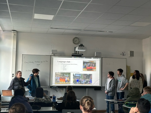 An image of students giving a presentation at the front of a classroom.