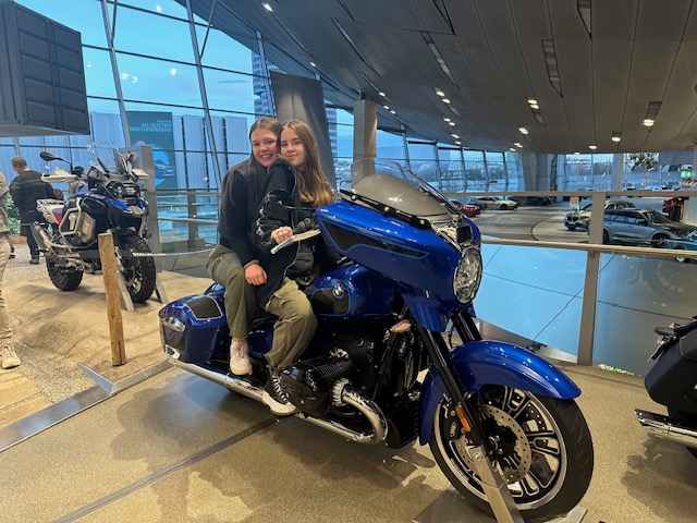 An image of students posing on a motorcycle at BMW World in Munich, Germany.