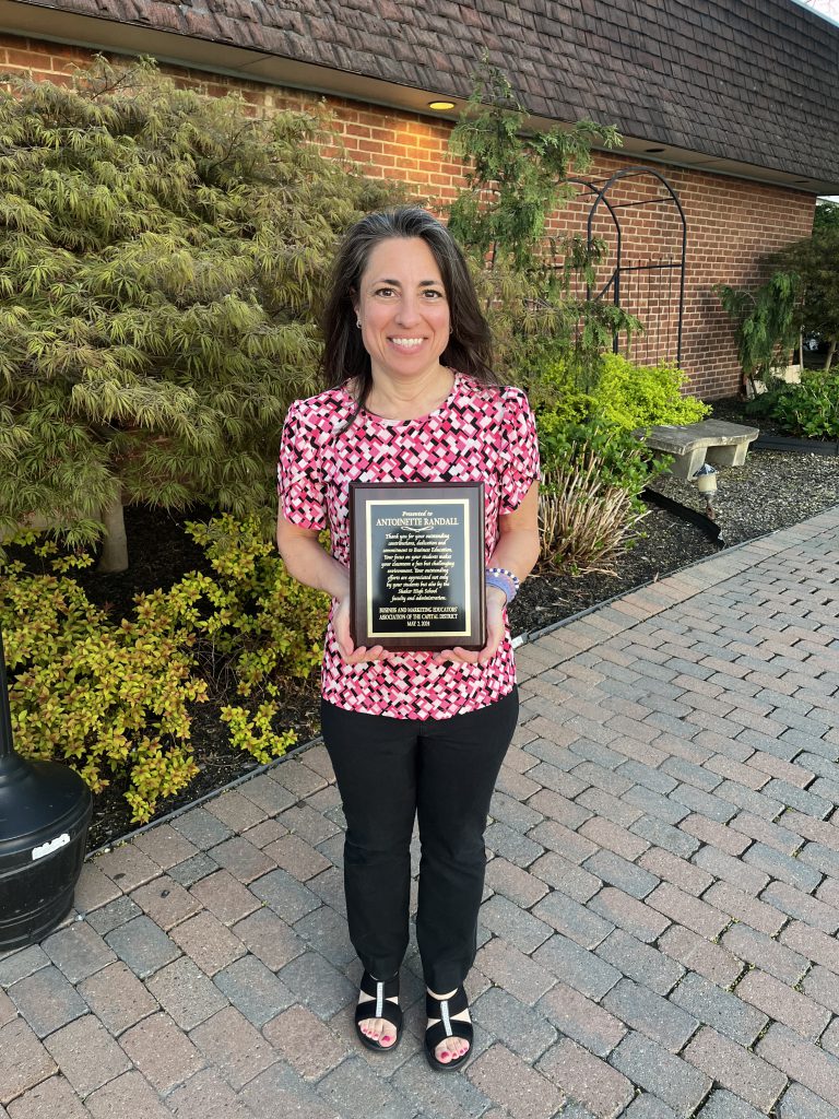 An image of Mrs. Antoinette Randall holding a plaque for her recognition as BMEA's Outstanding Business Educator of the Year.