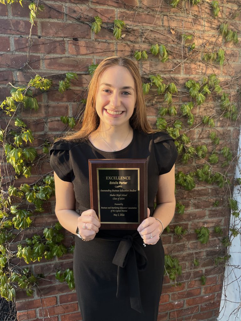 An image of Shaker senior Estelle Porter holding a plaque for her recognition as BMEA's Outstanding Business Education Student of the Year.