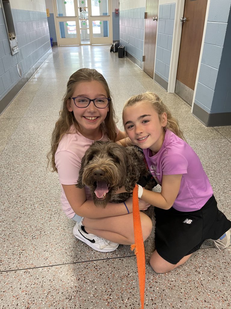Bunker the trained therapy dog with Loudonville students (two female).